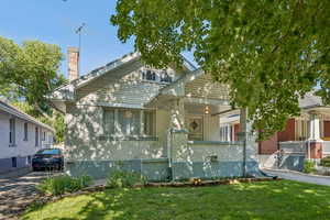 View of front facade featuring a chimney, brick siding, a front yard, and covered porch