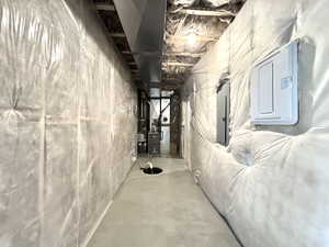 Unfinished basement with heating unit, electric panel, and gas water heater