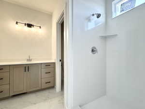 Bathroom with marble look tile flooring, a shower, and vanity