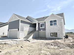 View of front of house with stone siding, board and batten siding, roof with shingles, and stairs