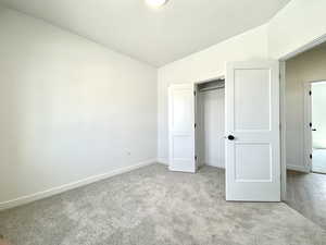 Unfurnished bedroom with carpet floors, vaulted ceiling, and a closet