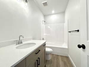 Bathroom featuring wood finished floors, vanity, and bathtub / shower combination