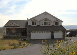 View of front facade featuring brick siding, driveway, a garage, a porch, and a shingled roof
