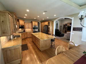 Kitchen with decorative backsplash, arched walkways, a center island, recessed lighting, and a kitchen breakfast bar