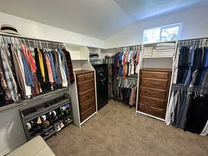 Spacious master closet with vaulted ceiling and carpet flooring