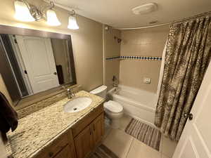 Full bath featuring a textured ceiling, tile patterned flooring, shower / bath combination with curtain, and vanity