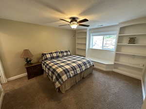 Carpeted bedroom featuring a textured ceiling, built-ins, and ceiling fan