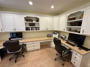 Office area featuring built in desk, light wood-style flooring, and recessed lighting