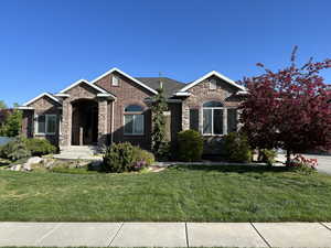 View of front of home with stone siding, brick siding, and a front lawn