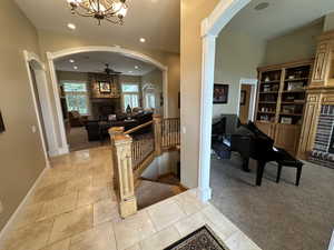 Hallway with arched walkways, light carpet, a chandelier, and recessed lighting