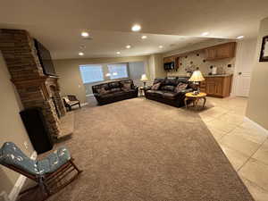 Family area featuring light tile patterned floors, recessed lighting, a fireplace, kitchenette, and light colored carpet