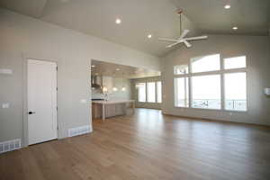 Open interaction with gourmet kitchen/dining area with light wood-style flooring, high vaulted ceiling, recessed lighting, and a ceiling fan
