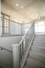 Stairway featuring a ceiling fan, lofted ceiling, and recessed lighting