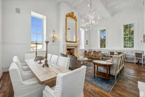 Dining area featuring dark wood-style floors, a high end fireplace, a decorative wall, beamed ceiling, and a wainscoted wall