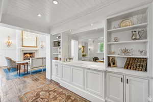 Bar area with built in features, hardwood / wood-style flooring, recessed lighting, wood ceiling, and a warm lit fireplace