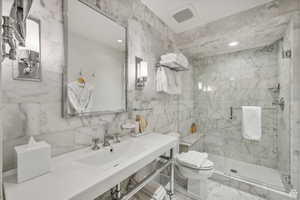 Bathroom with tile walls, a marble finish shower, marble look tiles, and recessed lighting