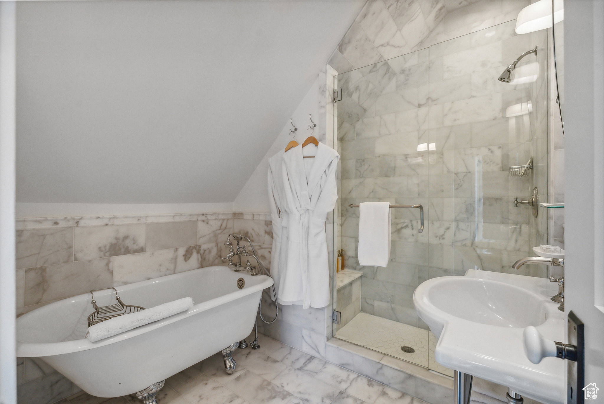Full bath with tile walls, a shower stall, a soaking tub, marble look tile flooring, and vaulted ceiling