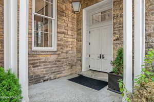 Entrance to property featuring stone siding, brick siding, and a porch