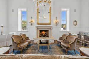 Sitting room featuring a decorative wall, wood finished floors, a wainscoted wall, plenty of natural light, and a high end fireplace