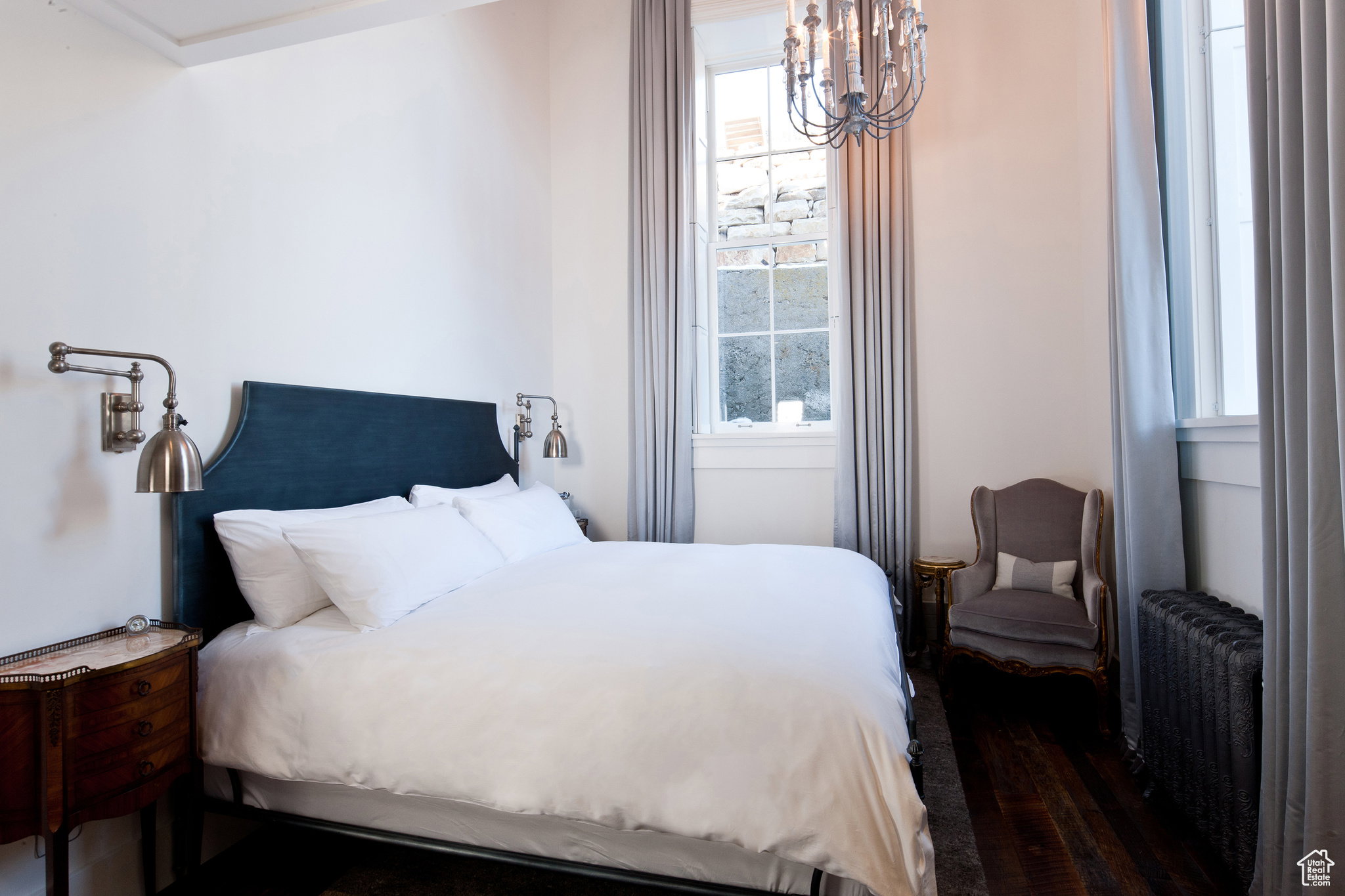 Bedroom with a chandelier, radiator heating unit, and wood finished floors
