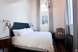 Bedroom with a chandelier, radiator heating unit, and wood finished floors