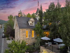 View of home's exterior with stone siding, a chimney, a standing seam roof, a metal roof, and outdoor dining area