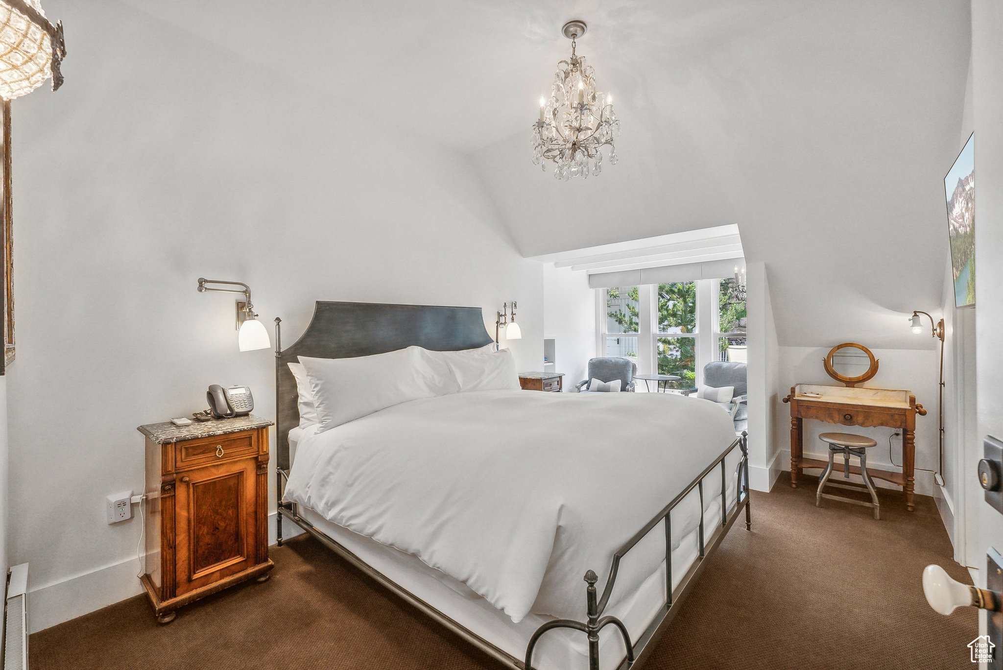 Bedroom with dark colored carpet, a chandelier, and vaulted ceiling