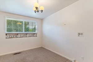 Empty room with carpet flooring and a chandelier