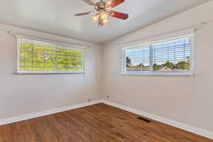 Unfurnished room featuring hardwood / wood-style flooring, lofted ceiling, and a ceiling fan