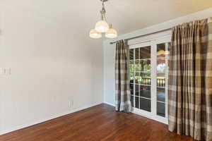 Empty room with wood finished floors and a chandelier