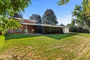 Rear view of house featuring a sunroom and a yard