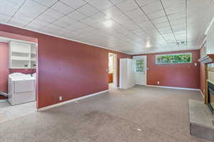 Unfurnished living room with washer and dryer, carpet flooring, and a tiled fireplace