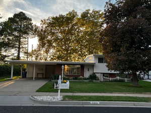 View of front of property with driveway, an attached carport, a fenced front yard, and covered porch