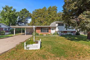Tri-level home with brick siding, concrete driveway, and a carport