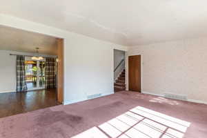 Carpeted spare room featuring baseboards and stairway