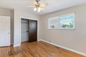 Unfurnished bedroom featuring hardwood / wood-style flooring, a closet, and ceiling fan
