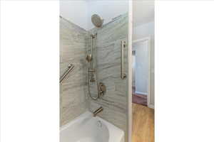 Bathroom featuring wood finished floors and bathtub / shower combination