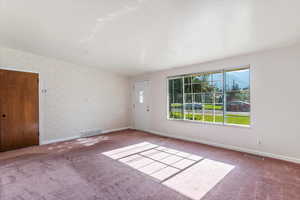 Carpeted spare room with baseboards and wallpapered walls