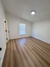 Spare room with light wood-style floors and lofted ceiling