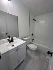 Bathroom featuring a textured ceiling, vanity, and  shower combination