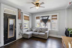Sitting room featuring dark wood-style flooring, ceiling fan, and baseboard heating