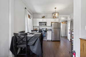 Kitchen with appliances with stainless steel finishes, dark wood-style floors, white cabinets, and decorative backsplash