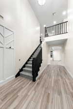 Stairs featuring wood finished floors, recessed lighting, and a high ceiling