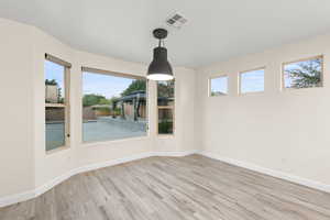 Unfurnished dining area featuring light wood-type flooring and baseboards