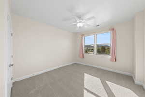 Carpeted empty room featuring baseboards and a ceiling fan