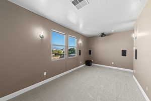 Home theater room with light colored carpet and a textured ceiling