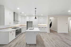 Kitchen with backsplash, wall chimney range hood, hanging light fixtures, white cabinetry, and recessed lighting