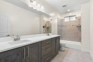 Full bath with double vanity, shower / tub combination, and light tile patterned floors