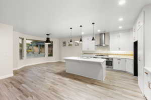 Kitchen with decorative backsplash, white cabinetry, recessed lighting, pendant lighting, and an island with sink