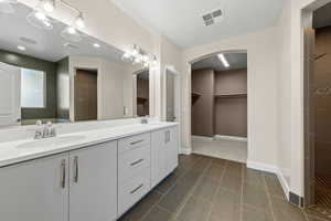 Bathroom with double vanity, a walk in closet, a tile shower, and recessed lighting